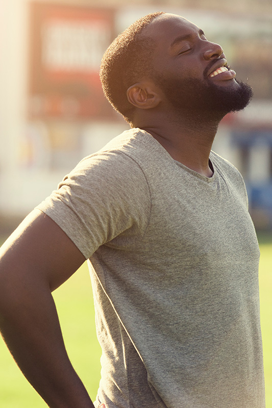 Allergic-Rhinitis-Treatment A black man in a t-shirt smiles and raises his face to the sun due to relief from allergies. Get treatment for allergic rhinitis from AZENA Health & Longevity in Gainesville.
