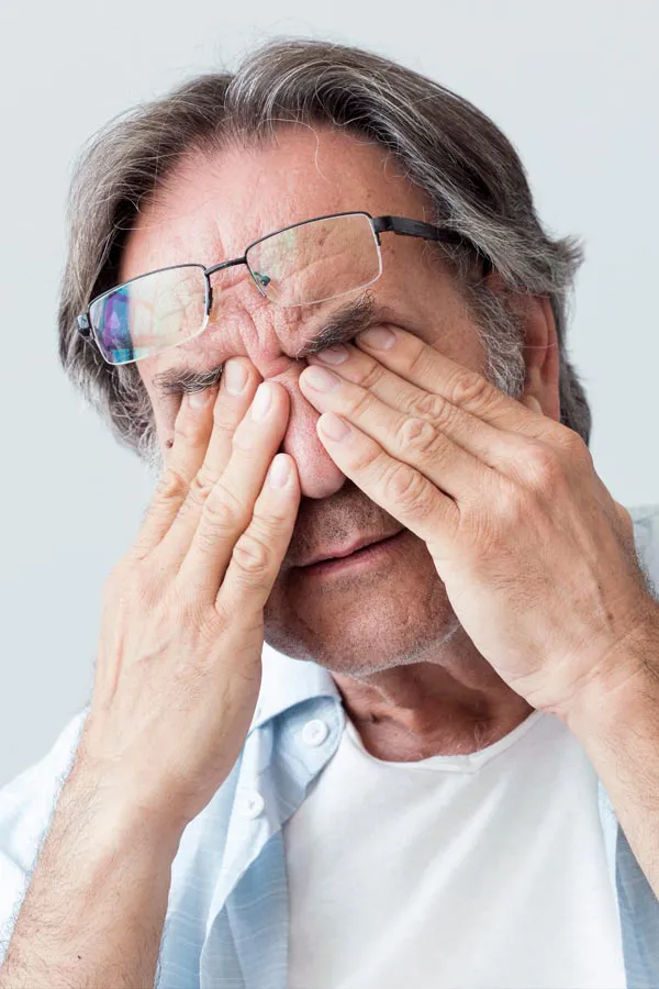 Chronic-Fatigue-Clinic A middle-aged man pushes his glasses onto his forehead and rubs his eyes with exhaustion. Get chronic fatigue treatment from AZENA Health & Longevity in Gainesville.