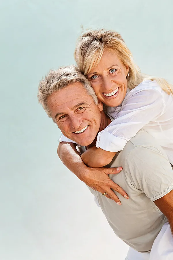 A happy mature couple having fun - the husband is carrying his wife on his back. Get treatment for food allergies from AZENA Health & Longevity in Gainesville.