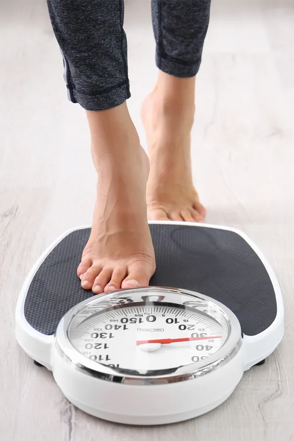 Obesity-Treatment Close up of feet stepping onto a scale. Receive expert functional medicine for obesity treatment by AZENA Health & Longevity in Gainesville.