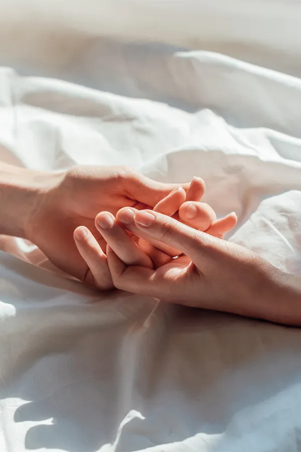 PT141-for-Women-Treatment A close up of a man and woman's hands lightly clasping on a bedsheet, representing successful PT141 sexual wellness treatment for women from AZENA Health & Longevity in Gainesville.
