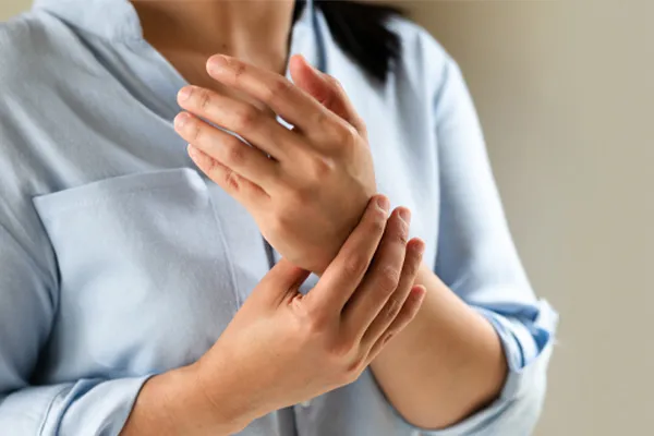 Rheumatoid-Arthritis-Clinic Close up of a woman in a blue blouse rubbing her wrist. Get rheumatoid arthritis treatment from AZENA Health & Longevity in Gainesville.