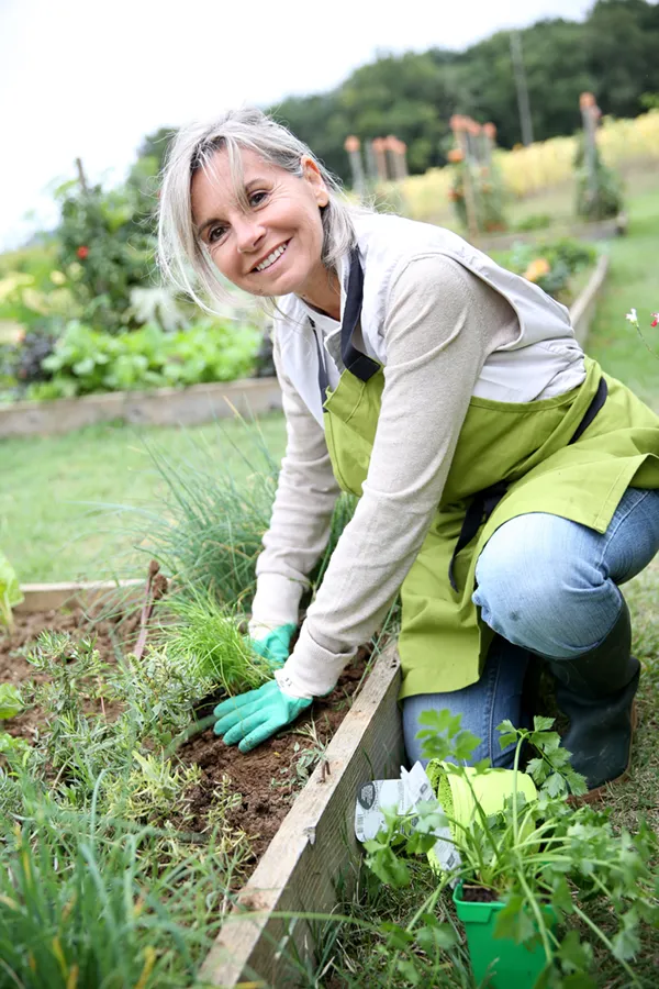 Rheumatoid-Arthritis-Treatment A mature woman bending down working on her garden happily after successful rheumatoid arthritis treatment from AZENA Health & Longevity in Gainesville.