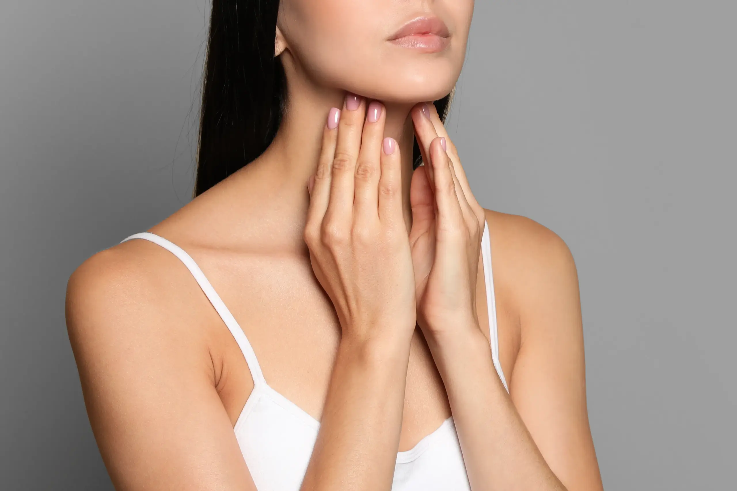 Thyroid-Doctor A woman in a white tank top touches her neck looking for signs of thyroid disorder. Get help for thyroid disorders from AZENA Health & Longevity in Gainesville.